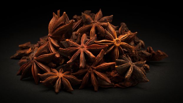 Pile of Organic Star anise or Chakra Phool (Illicium verum) on dark background.