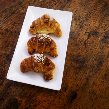 three sweet croissant on a rectangualr white dish