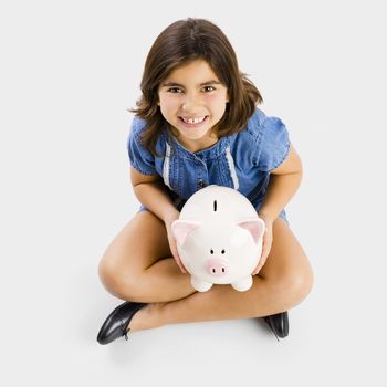 Young girl sitting on floor and holding a piggybank