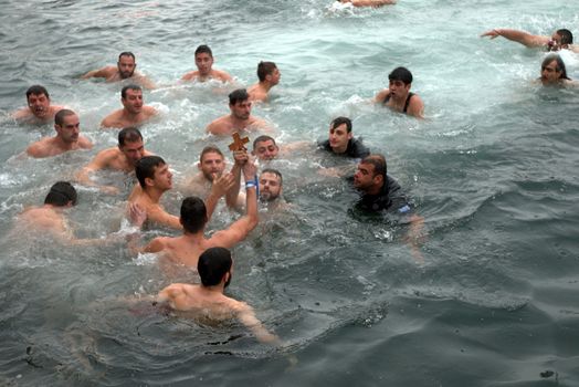 GREECE, Thessaloniki : A swimmer holds in the air a wooden cross he retrieved from the sea, during the blessing of the water ceremony marking the Orthodox Epiphany Day, in Greece's northern port of Thessaloniki on January 6, 2016.Similar celebrations for the Epiphany Day are held across the country and region on river banks, seafronts and lakes.