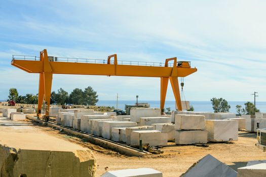 Industrial marble quarry, with cut blocks and workers and machines bulldozer at work.
