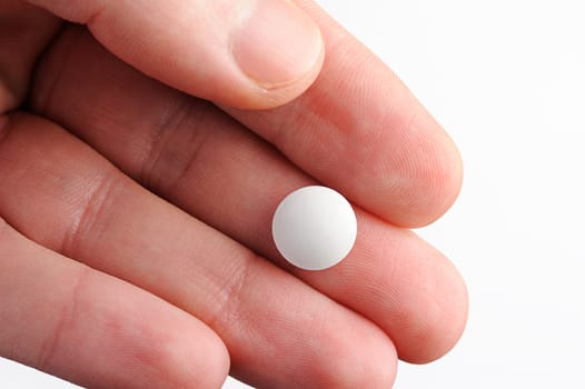 round white pill lay on hand on white background