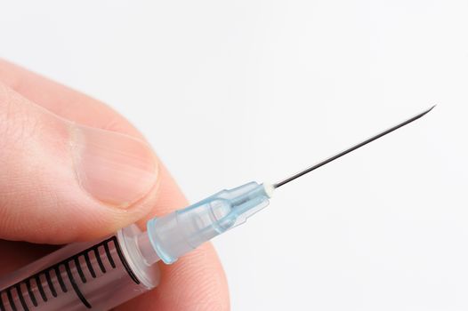 macro of syringe with needle in hand on white