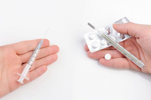  thermometer, syringe, and pills on hands on white