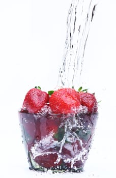 Red strawberry in a glass with water on white background