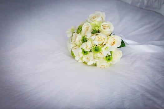 Wedding bouquet of white roses on a white veil