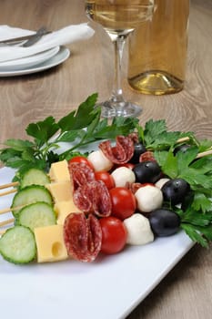 Appetizer of salami with mozzarella, olives, cherry tomatoes, cucumber and cheese on a skewer