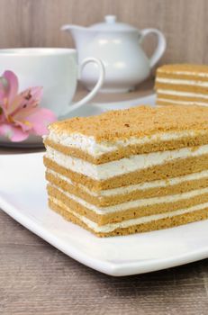 Piece of honey cake with a cup of coffee on a table with a flower