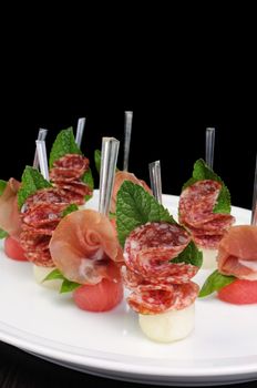 Canape of watermelon balls with a melon with gammon and salami