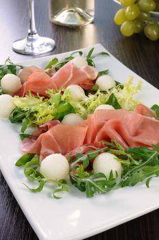 Salad of arugula, lettuce, ham with melon