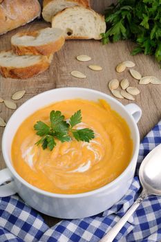 Pumpkin puree soup with  parsley  a plate on the table with bread