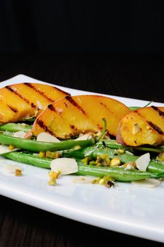 Salad of green beans , peaches, almonds, pistachios and sprinkled with Parmesan