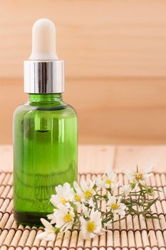 Bottle serum for beauty Spa and therapy treatment wiht wildflowers  on wooden background.