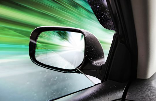 car driving on empty road, rear-view mirror in rainy weather