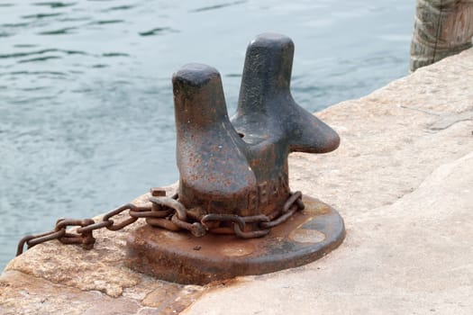 Old and rusted.

Iron bollard and chain in the port of Looe, Cornwall, used to tying up of boats to harbour.