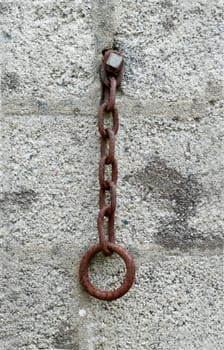 Old and rusted.

Old iron chain and ring hanging on farm wall.