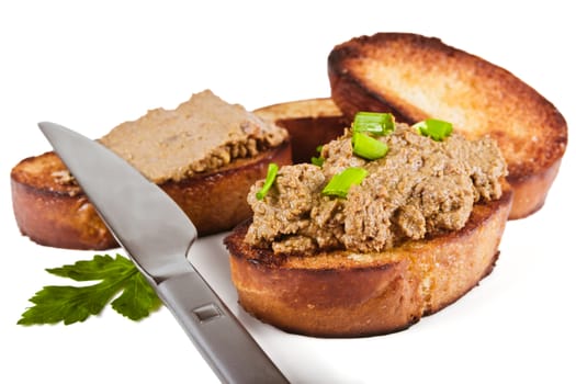 Fried bread with liver pate, green onions and parsley leaves on a white background