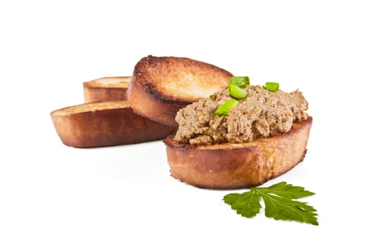 Fried bread with liver pate, green onions and parsley leaves on a white background