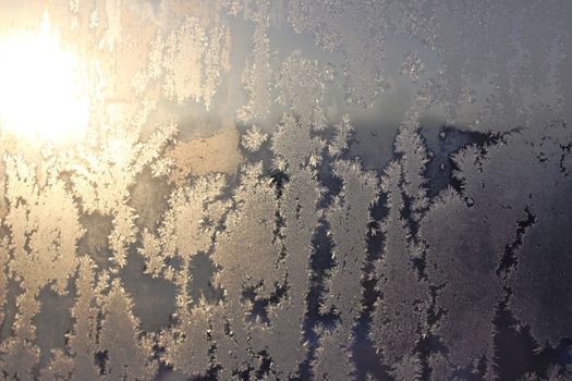 Frozen white window covered with frost in winter patterned.