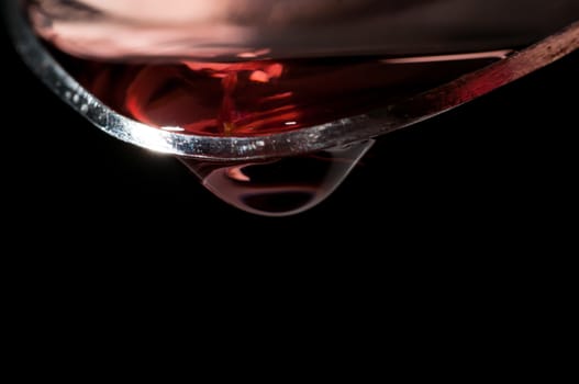 Droplet of Red medicine falling from a large silver spoon