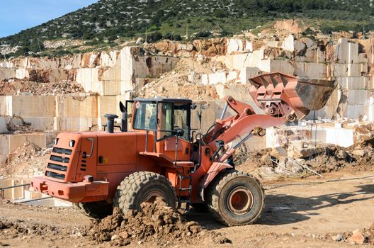 Industrial marble quarry, with cut blocks and workers and machines bulldozer at work.