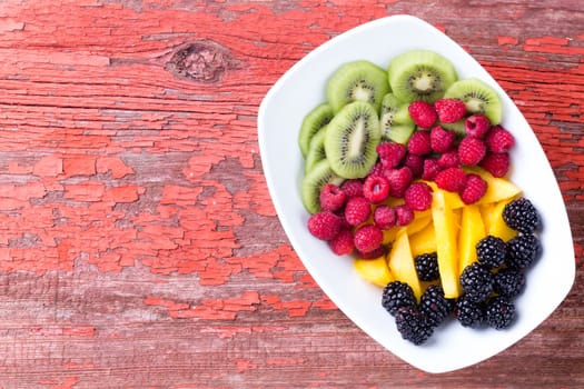 Top view of berries, kiwi and melon in plate