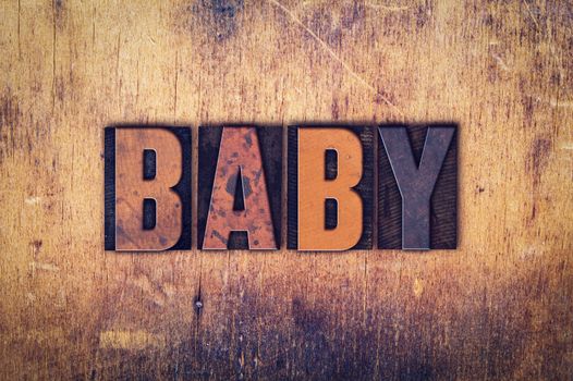 The word "Baby" written in dirty vintage letterpress type on a aged wooden background.