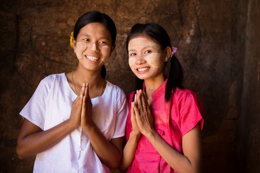 Two young Myanmar women in a traditional welcoming gesture.