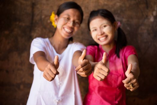 Portrait of two beautiful Myanmar girls smiling and giving thumb up.