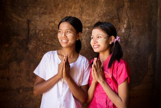 Two young Myanmar girls in a praying gesture.
