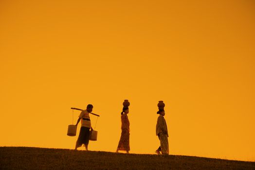 Silhouette of Asian traditional farmers carrying clay pots on head going back home, Bagan, Myanmar