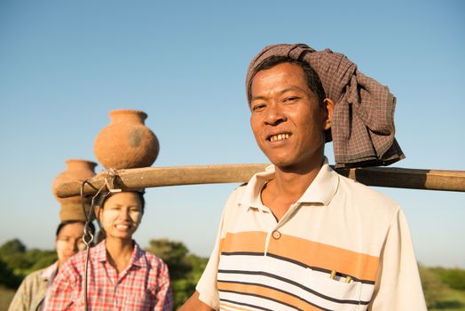 Portrait of group Asian Burmese traditional farmers carrying clay pots on head, Bagan, Myanmar