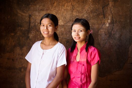 Portrait of two beautiful young traditional Myanmar girls smiling. 