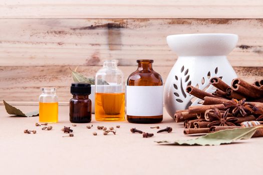 Bottle of essential oil with cinnamon stick ,star anise and bay leaves with selective focus on old wooden background .