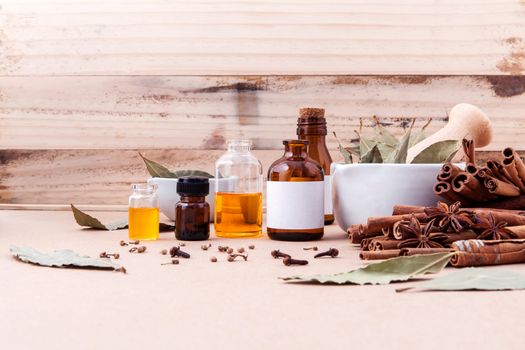 Bottle of essential oil with cinnamon stick ,star anise ,bay leaves with selective focus on old wooden background .