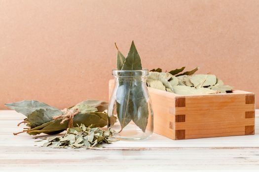 Bottle of dried bay leaves and wooden box with selective focus on wooden background.