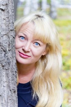 European blond woman with long hair on tree background