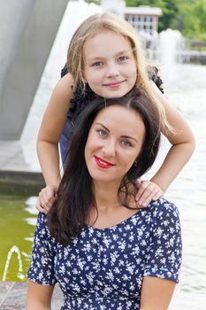 Embracing brunette mother and blond daughter with long hairs