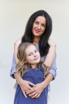 Embracing brunette mother and blond daughter with long hairs