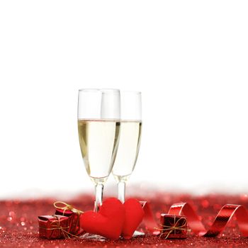 Glasses with Champagne and handmade hearts on red glitters isolated on white background