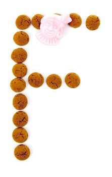 Ginger nuts, pepernoten, in the shape of letter F isolated on white background. Typical Dutch candy for Sinterklaas event in december