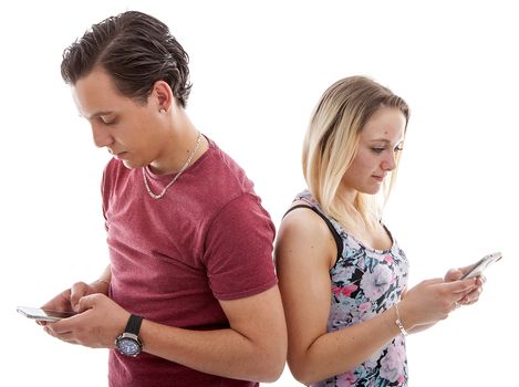 Young couple in disinterest moment with mobile smart phones over white background