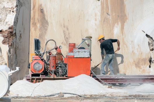 Industrial marble quarry, with cut blocks and workers and machines at work.