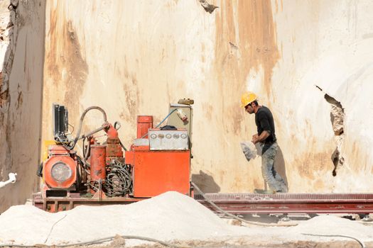 Industrial marble quarry, with cut blocks and workers and machines at work.