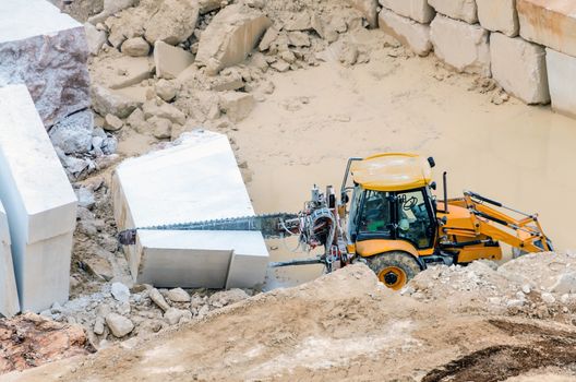 Industrial marble quarry, with cut blocks and workers and machines bulldozer at work.