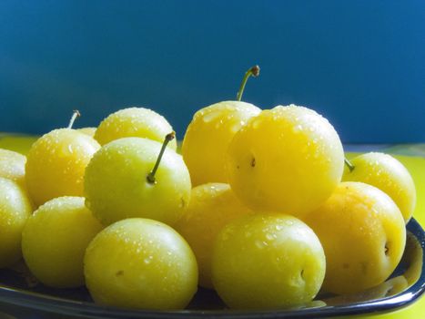 Fresh small yellow plums with water drops