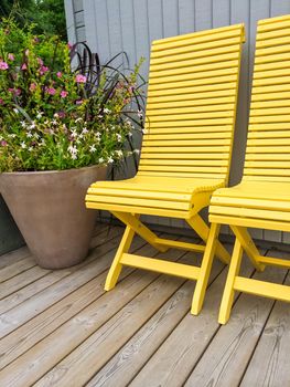 Patio decorated with yellow chairs and flowers. House exterior.