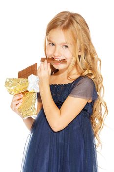 Beautiful blonde girl in a blue dress with curls eating a chocolate