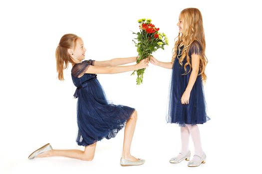 Two charming little girls in a blue dresses with a bouquet of flowers