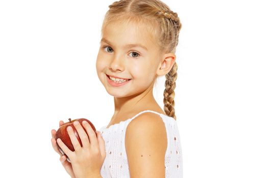 Cute little girl in a white dress bites red fresh apple